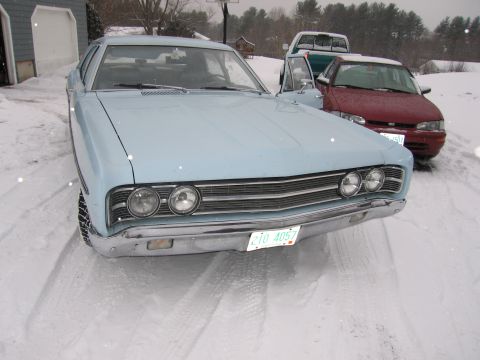1991 Ford LTD Crown Victoria - A light blue sedan with a distinctive grille and dual headlights sits in the snow, with other vehicles behind it.