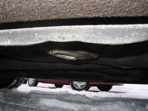 1991 Ford LTD Crown Victoria - Underside of a car in the snow, with another vehicle partially visible.
