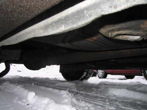 1991 Ford LTD Crown Victoria - The undercarriage of a vehicle is shown, with snow on the ground and another car in the background.