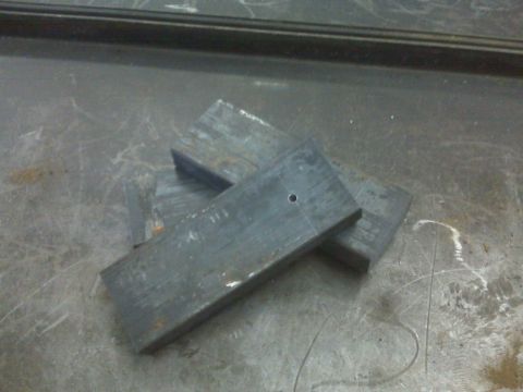 1996 Ford Bronco - Several metal plates are stacked on a workbench, with one plate a single drilled hole.