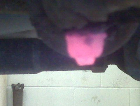 1996 Ford Bronco - A close-up view of a vehicle's exhaust pipe emitting a bright pink glow.