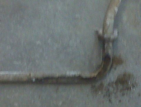 1996 Ford Bronco - Close-up of a rusted metal pipe with a flange, possibly a component from a vehicle or industrial equipment.