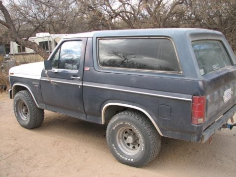 1982 Ford Bronco - A dark blue and white Ford Bronco is parked outdoors, viewed from its side profile.
