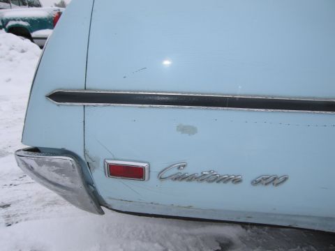 1991 Ford LTD Crown Victoria - The rear of a light blue car shows "Custom 500" badging and a chrome bumper, with snow on the ground and another vehicle visible.