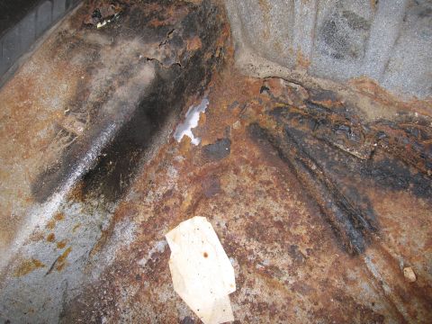 1991 Ford LTD Crown Victoria - The vehicle's floor pan shows extensive rust damage and holes, indicating poor condition.