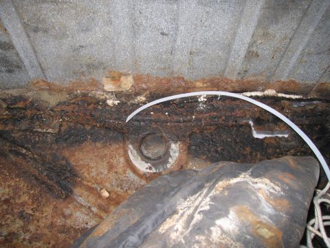 1991 Ford LTD Crown Victoria - Undercarriage view showing significant rust and a black object, possibly a tire or cover.