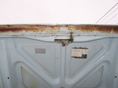 1991 Ford LTD Crown Victoria - The underside of a car hood shows significant rust along the top edge and two warning labels.