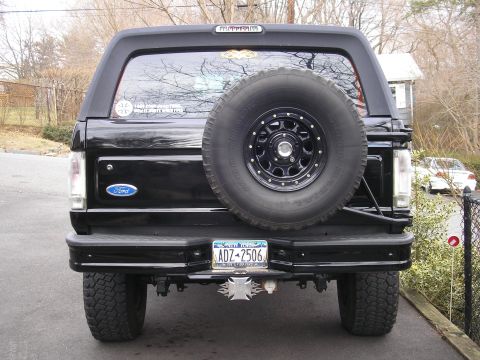 1995 Ford Bronco - Rear view of a black 1995 Ford Bronco, showing the spare tire and license plate.
