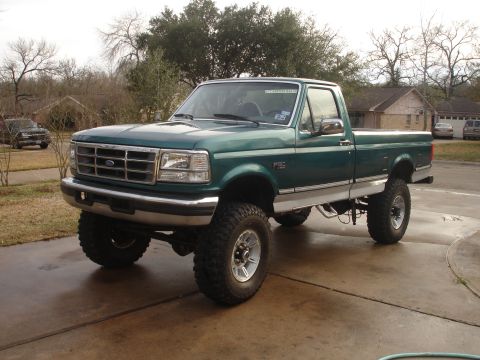1996 Ford F-150 - This lifted 1996 Ford F-150 pickup truck is shown in a three-quarter front view, highlighting its substantial tires and green paint.