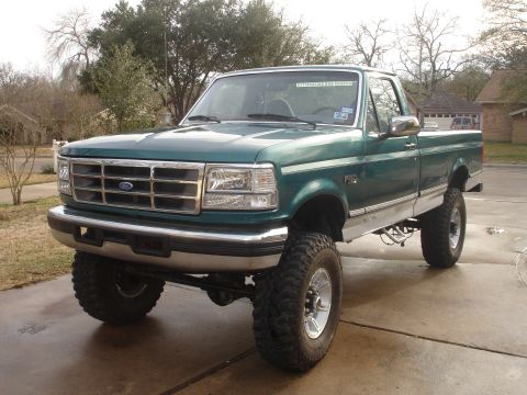 1996 Ford F-150 - This lifted Ford pickup truck is shown from a front three-quarter angle on a paved driveway.