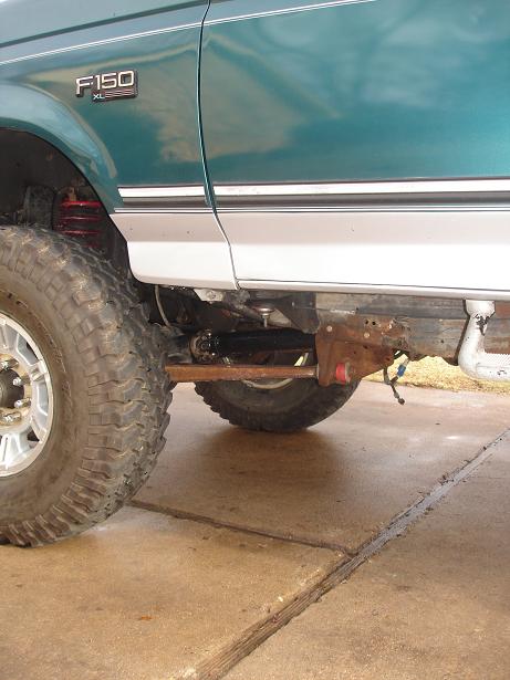 1996 Ford F-150 - Side view of a teal and silver Ford F-150 XL pickup truck, showing the front wheel and suspension components.