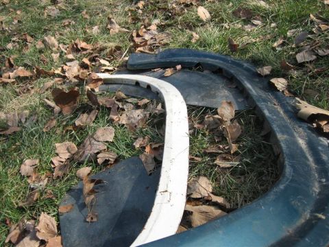 1900 Yugo Vega - Car fender parts are scattered on the ground, covered in dry leaves.