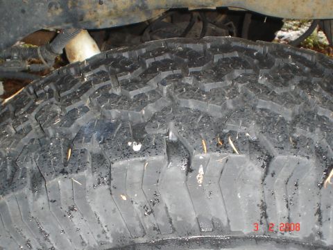 1990 Ford Bronco - A close-up view of a vehicle's tire tread, showing dirt and debris embedded in the rubber.