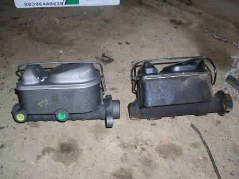 1979 Ford Bronco - Two brake master cylinders are shown side-by-side on a concrete surface.