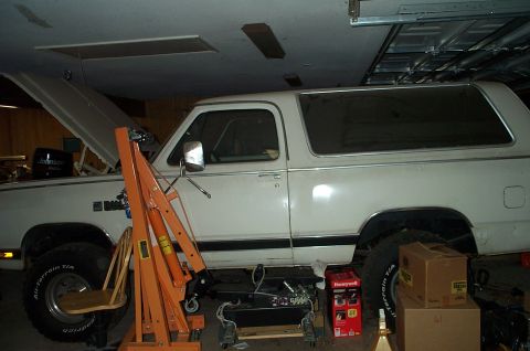 1996 Ford Bronco - White SUV in a garage with its hood open and an engine hoist positioned next to it.