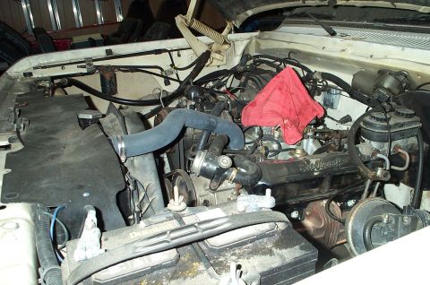 1996 Ford Bronco - Engine bay detail with a red rag placed on the engine. The battery is in the foreground.
