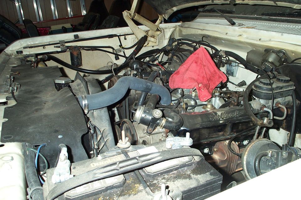 Engine bay with a red rag draped over the engine block. Battery is visible in the foreground