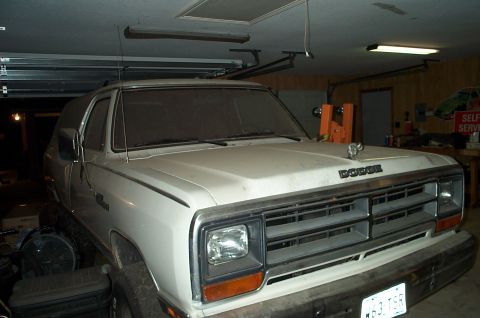 1996 Ford Bronco - A white Dodge Ramcharger SUV is parked in a garage, showing its front grille and hood.