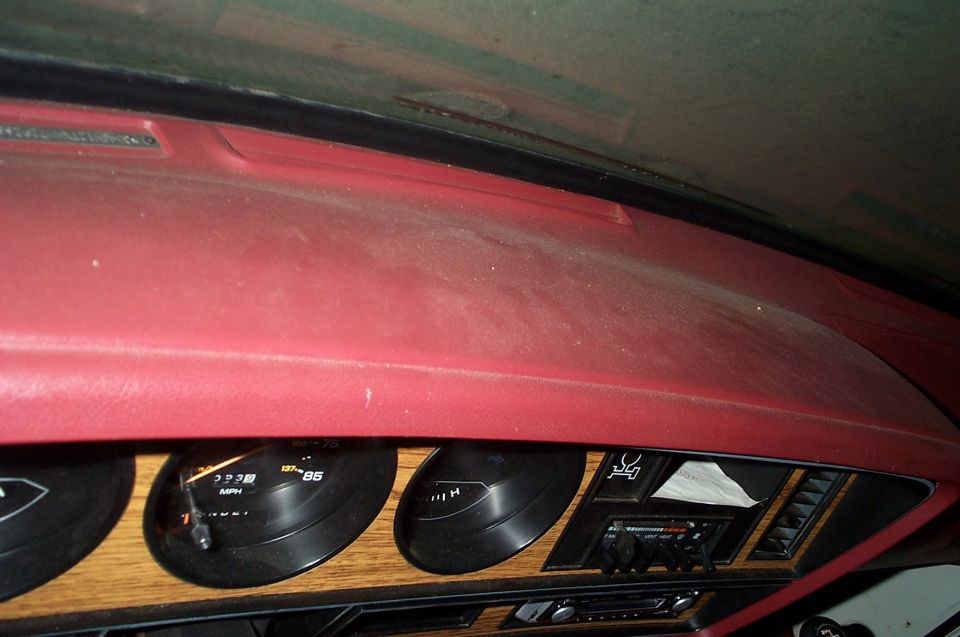 Dashboard with gauges, radio, and wood trim. A piece of paper is tucked into a vent