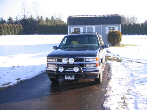 1998 Chevrolet Tahoe - A black SUV with a bull bar and auxiliary lights is parked in front of a shed on a snowy day.