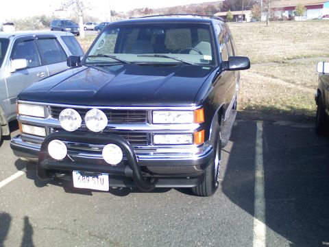 1998 Chevrolet Tahoe - Front view of a black Chevrolet Tahoe, equipped with a bull bar and auxiliary lights. Another vehicle is parked to the left.