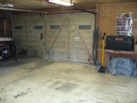 1988 Ford Bronco - The interior of a garage is shown, a large overhead door and various items stored within.