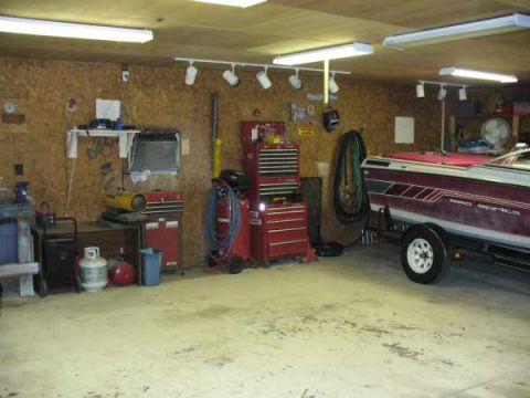 1988 Ford Bronco - A boat on a trailer is parked inside a garage, surrounded by various tools and equipment.