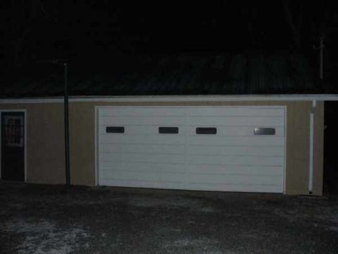 1988 Ford Bronco - Exterior view of a garage with a white double door at night.