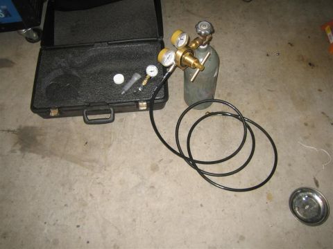 1987 Suzuki Samurai - A welding gas cylinder, regulator, and hose are laid out next to an open carrying case on a concrete floor.