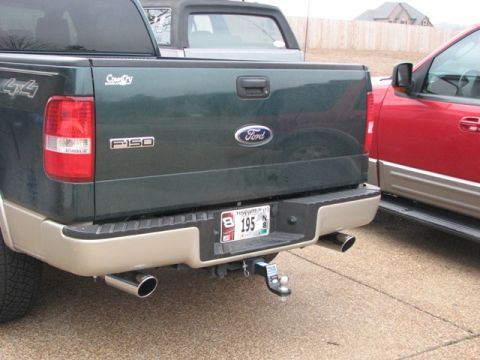 1991 Ford Bronco - The rear of a Ford F-150 pickup truck is shown, parked next to a red SUV.