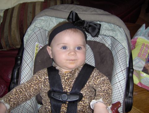1978 Ford Bronco - A baby with blue eyes and a black bow is secured in a car seat, with a package of diapers visible in the background.