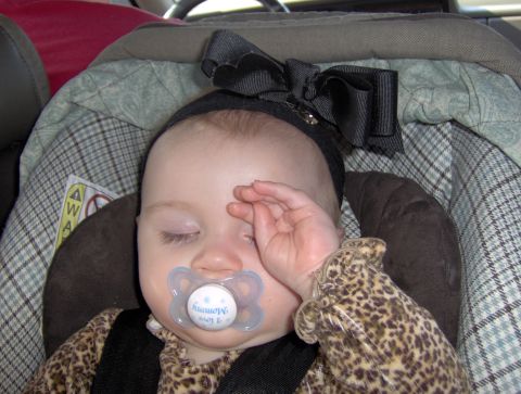 1978 Ford Bronco - Baby sleeping in a car seat with a pacifier and a large bow on its head.