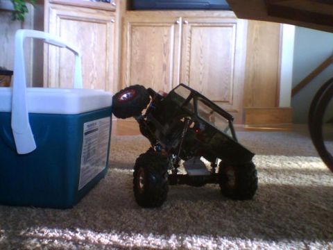 1993 Ford Bronco - A remote control rock crawler toy is positioned next to a cooler on a carpeted floor.