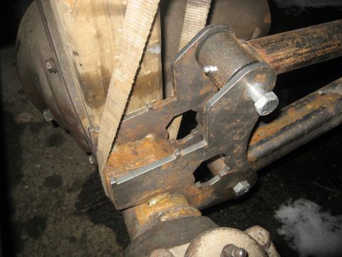 1990 Ford F-250 - A custom suspension bracket is bolted onto a vehicle's axle, with a strap holding it in place.