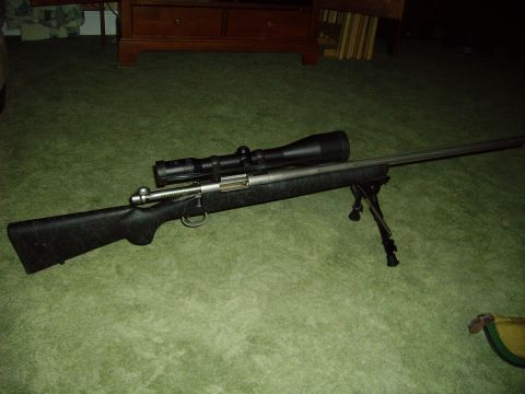 1991 Ford Bronco - A rifle with a scope and bipod is displayed on a green carpeted floor.