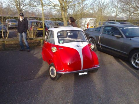 1991 Ford Crown Victoria - A classic red and white BMW Isetta is parked in a lot next to a modern Ford Mustang.