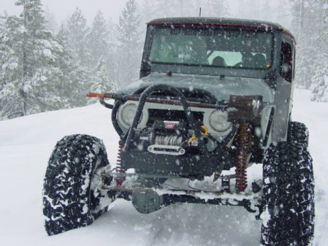 1986 Ford Bronco - An off-road vehicle navigates a snowy landscape with heavy snowfall.