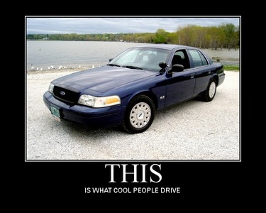 2003 Ford Crown Victoria - A blue Ford Crown Victoria is parked on a gravel lot near a lake.