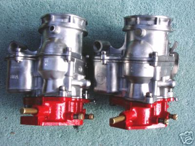 1953 Ford Mainline - Two carburetors are shown, each with a silver body and a red base, against a textured background.