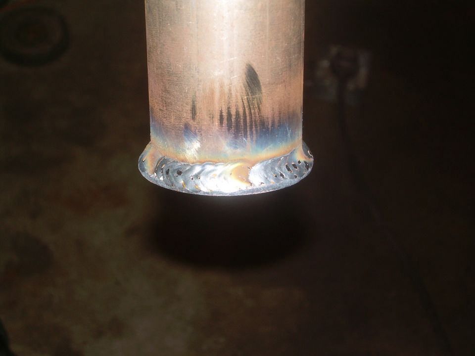 Close-up of a metal pipe with a welded flange and visible weld marks