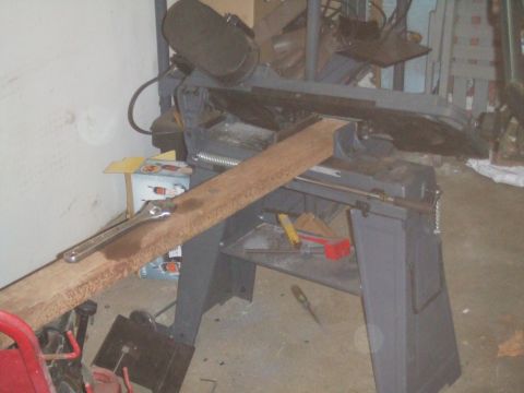 1996 Ford Bronco - Metal cutting bandsaw with a piece of wood clamped in place for cutting.