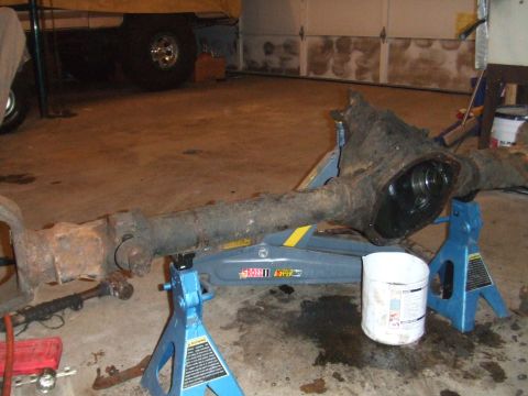 1996 Ford Bronco - A vehicle's front axle assembly is disassembled and supported by jack stands in a garage setting.