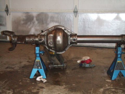 1996 Ford Bronco - A rear axle assembly is supported by jack stands in a garage setting, possibly undergoing maintenance or modification.