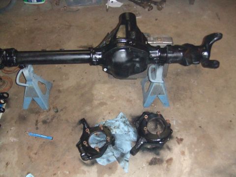 1996 Ford Bronco - A freshly painted rear axle assembly and knuckle components are laid out on the garage floor.