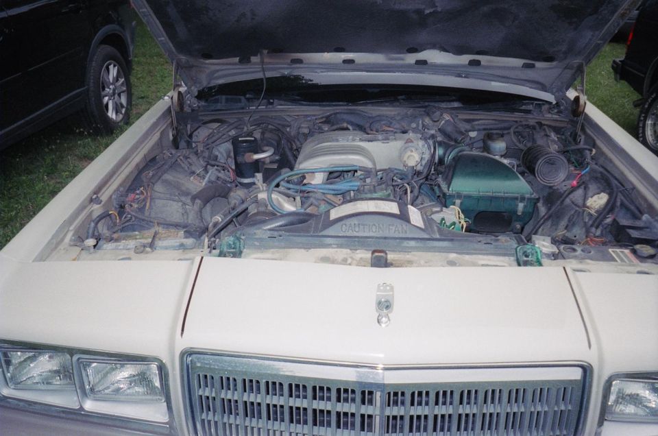 Open engine bay of a cream-colored full-size sedan