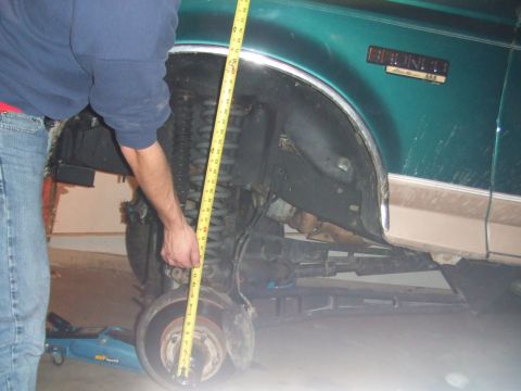 1996 Ford Bronco - A person measures the suspension height of a green 1996 Ford Bronco.