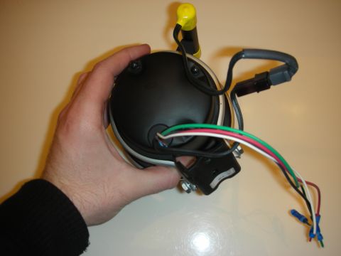 1998 Ford Crown Victoria - hand holds the back of a pedestal tachometer, displaying its wiring harness and mounting bracket.