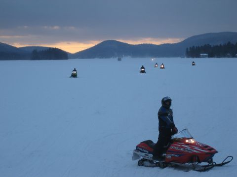 1995 Ford Bronco - Multiple snowmobiles are visible on a vast, snow-covered expanse under a cloudy sky at dusk.