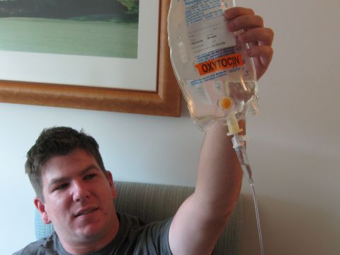 1987 Suzuki Samurai - A man holds an IV bag containing oxytocin while seated in a room with a framed picture on the wall.