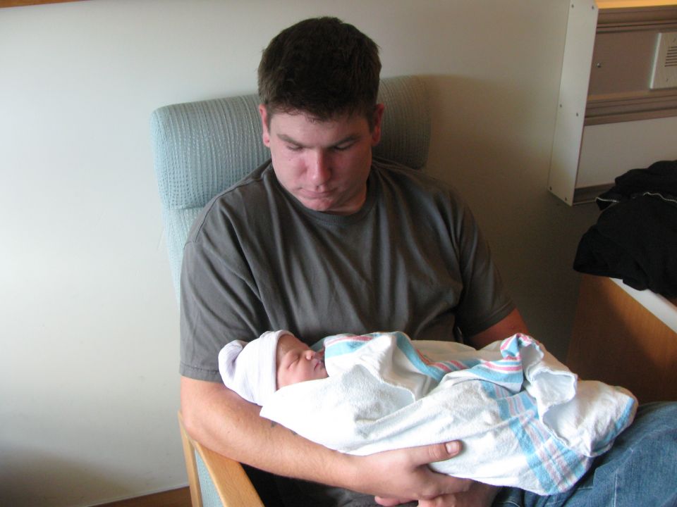 Man in a chair holding a swaddled baby
